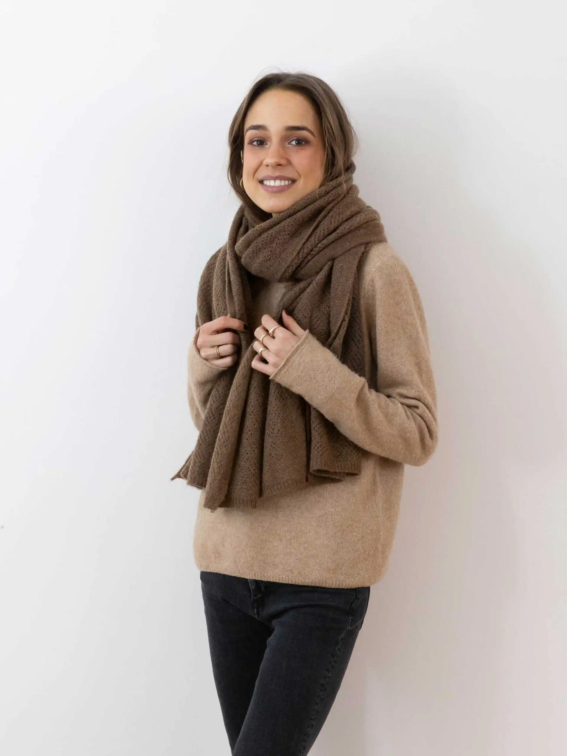 Femme portant un châle yack marron chocolat, vêtue d'un pull beige et posant devant un fond blanc. Cette étole en laine 100 % mongole est parfaite pour se réchauffer avec style en hiver.
