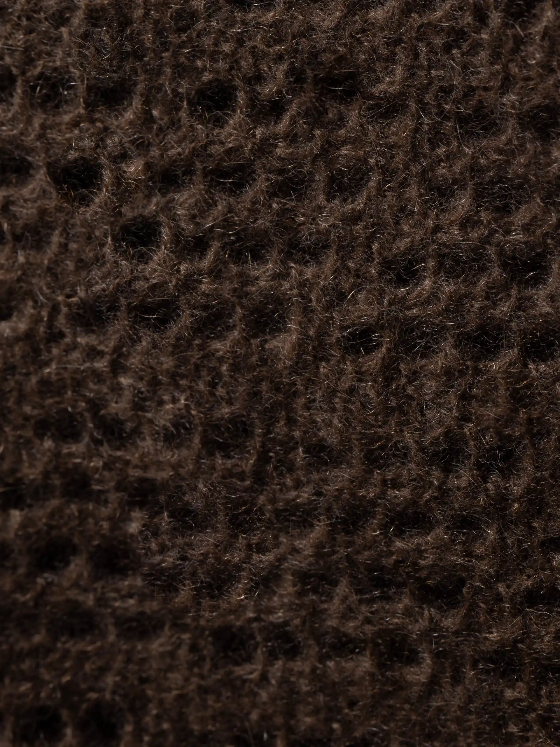 Gros plan sur la texture tricotée de l'étole yack marron foncé point pointelle, montrant la finesse et la qualité de la laine de yak mongole. Une étole chaude et douce, idéale pour l'hiver.