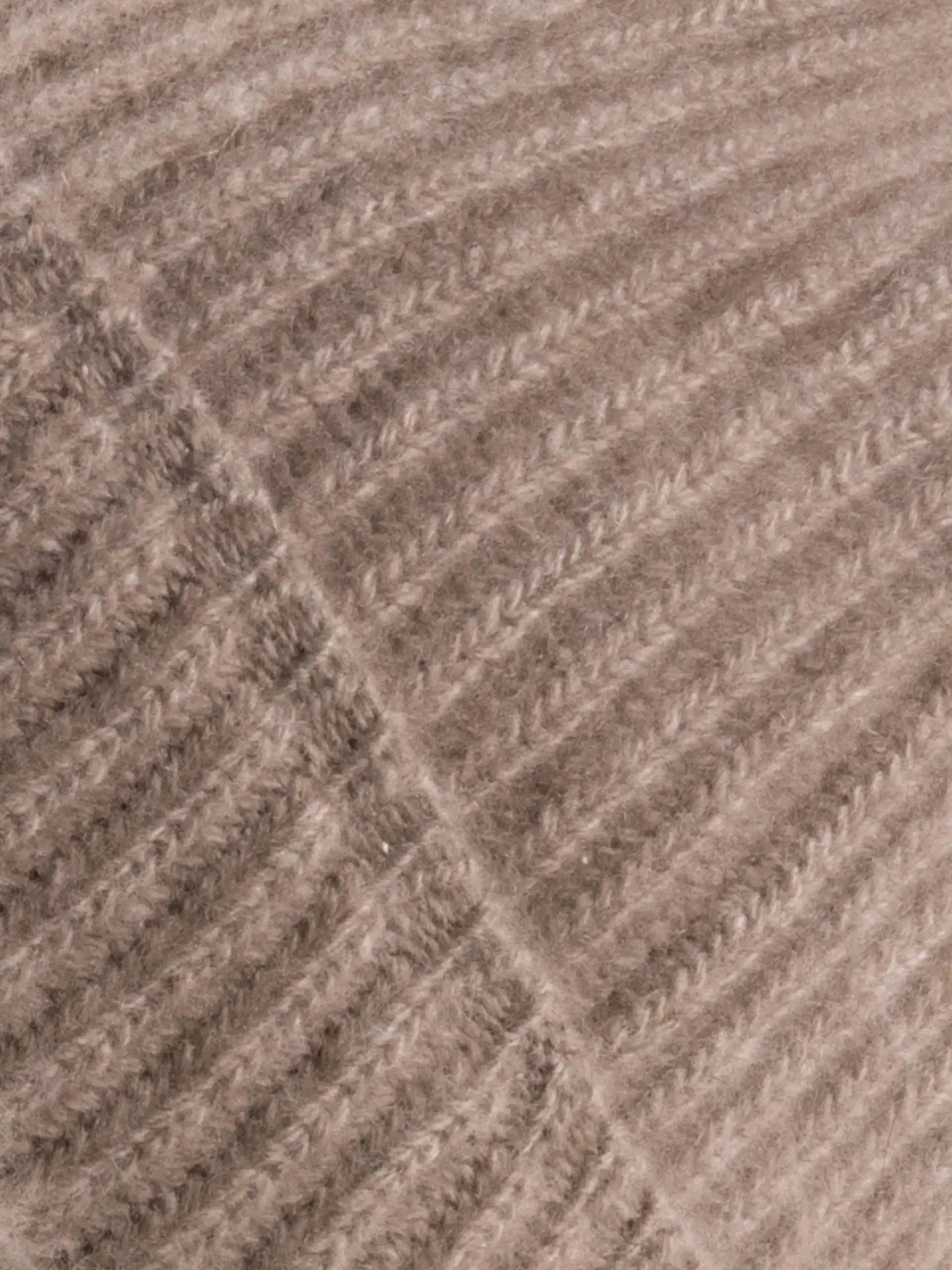 Gros plan sur la texture du tricot de notre bonnet en cachemire greige, montrant la finesse du tissage et la qualité du matériau.