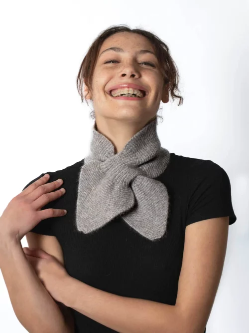Femme souriante portant une écharpe cachemire papillon Beige, confortable et chaleureuse.