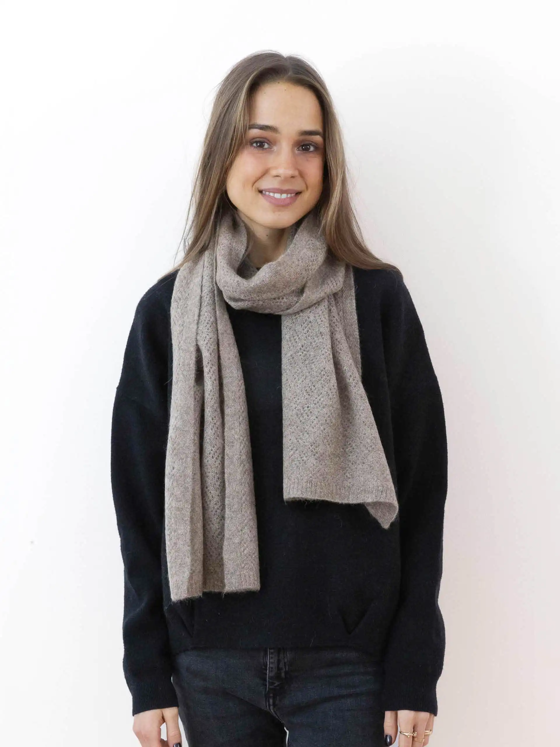 Une femme souriante portant une écharpe yack fine gris cendré.