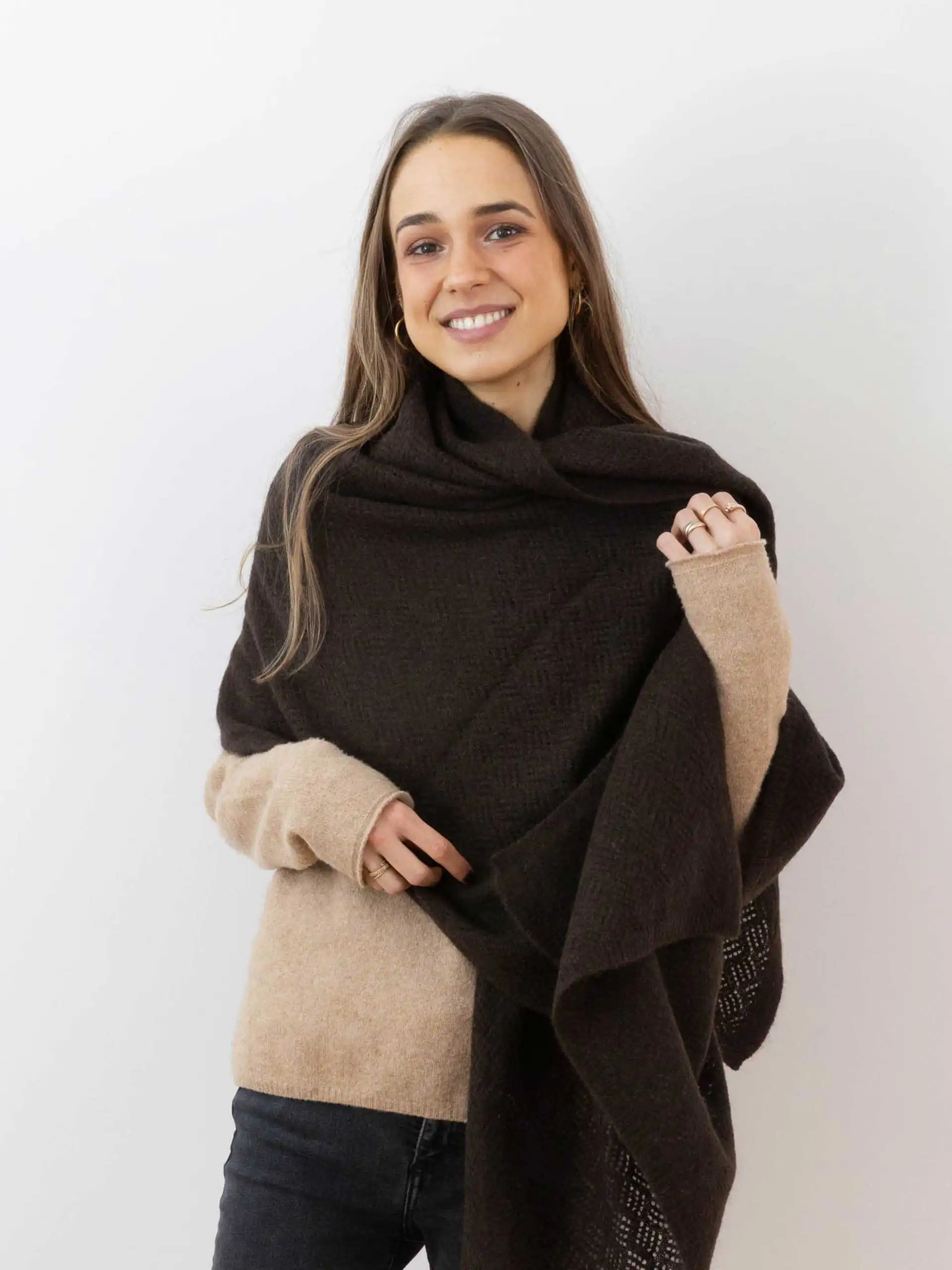 Femme souriante portant une étole yack marron foncé point pointelle, vêtue d'un pull beige et posant devant un fond blanc. Cette étole en laine 100 % mongole est parfaite pour se réchauffer avec style en hiver.