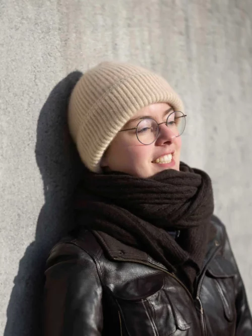 Femme souriante portant un bonnet cachemire beige et une écharpe noire
