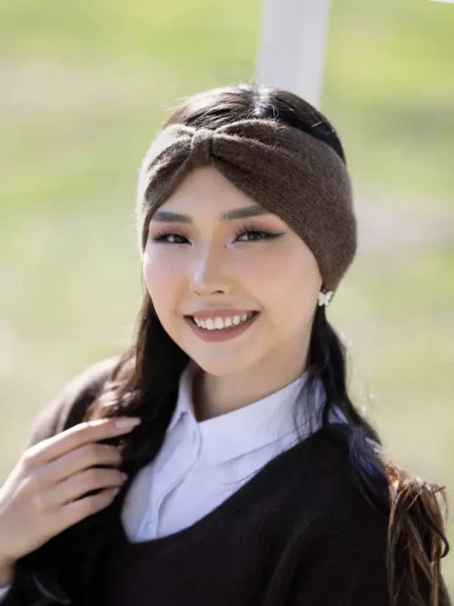 Femme souriante portant un bandeau marron chocolat en laine, accessoire chic pour l'hiver.