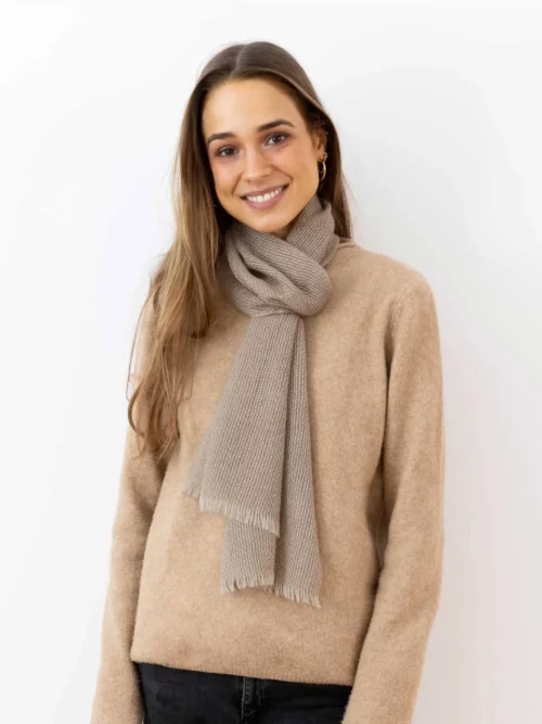 Femme souriante portant une écharpe cachemire à franges beige