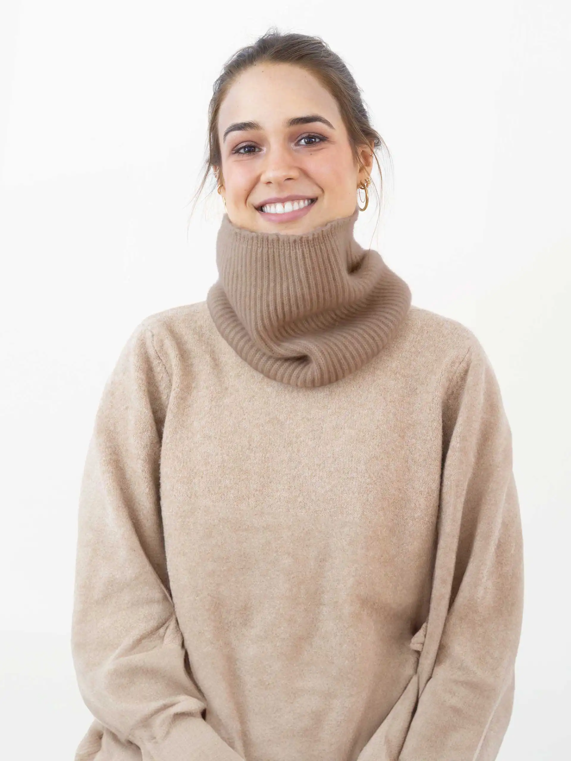 Une femme souriante portant un tour de cou en cachemire beige, vêtu d'un pull assorti. Idéal pour rester au chaud avec style.