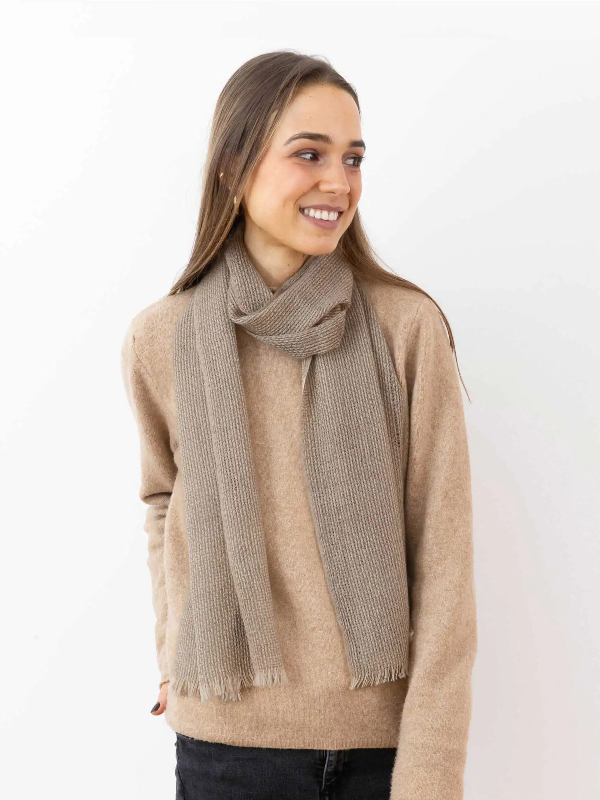 Femme souriante en pull beige avec une écharpe cachemire à franges