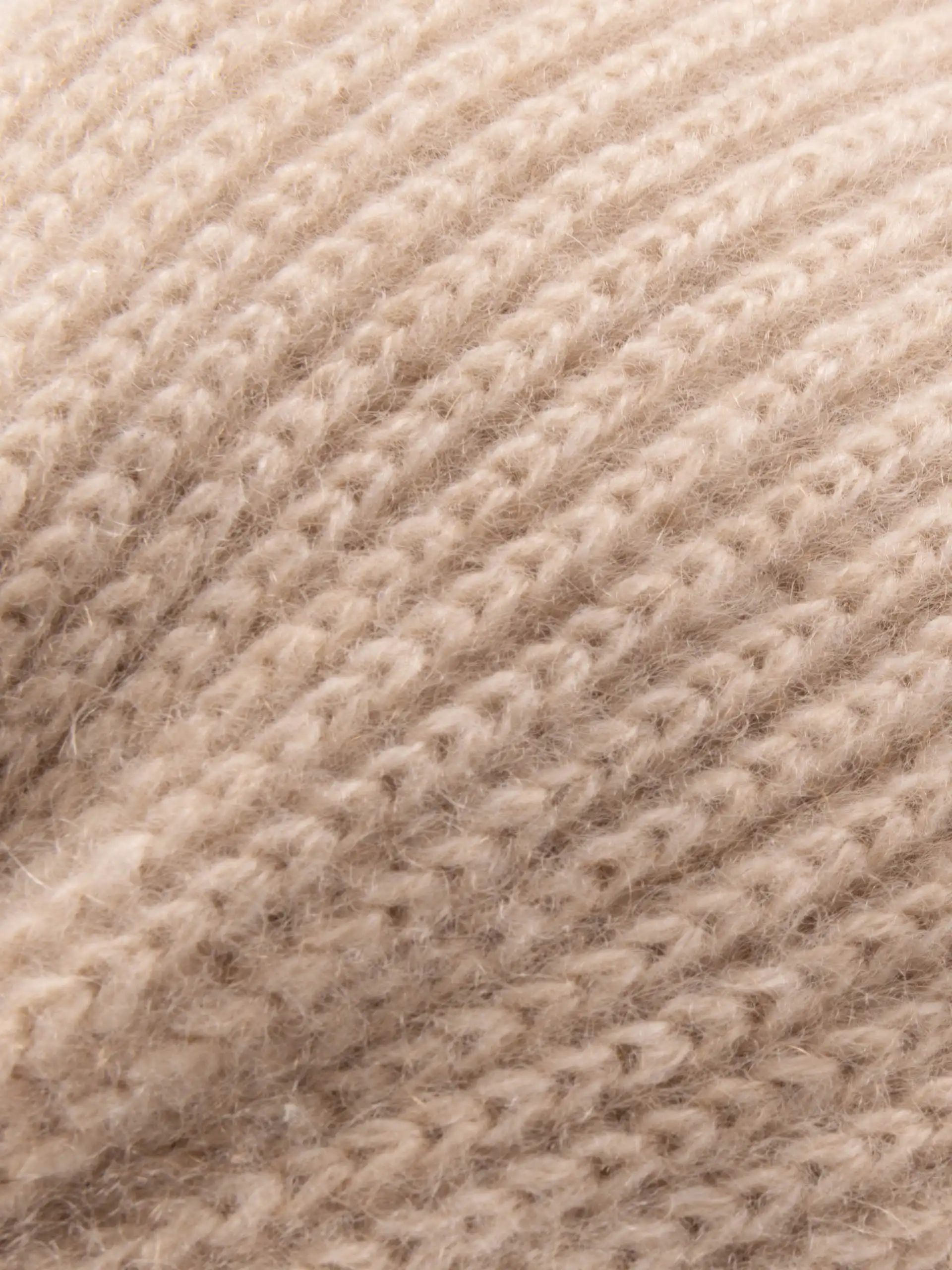 Gros plan sur la texture tricotée du bandeau cachemire beige, doux et chaud.