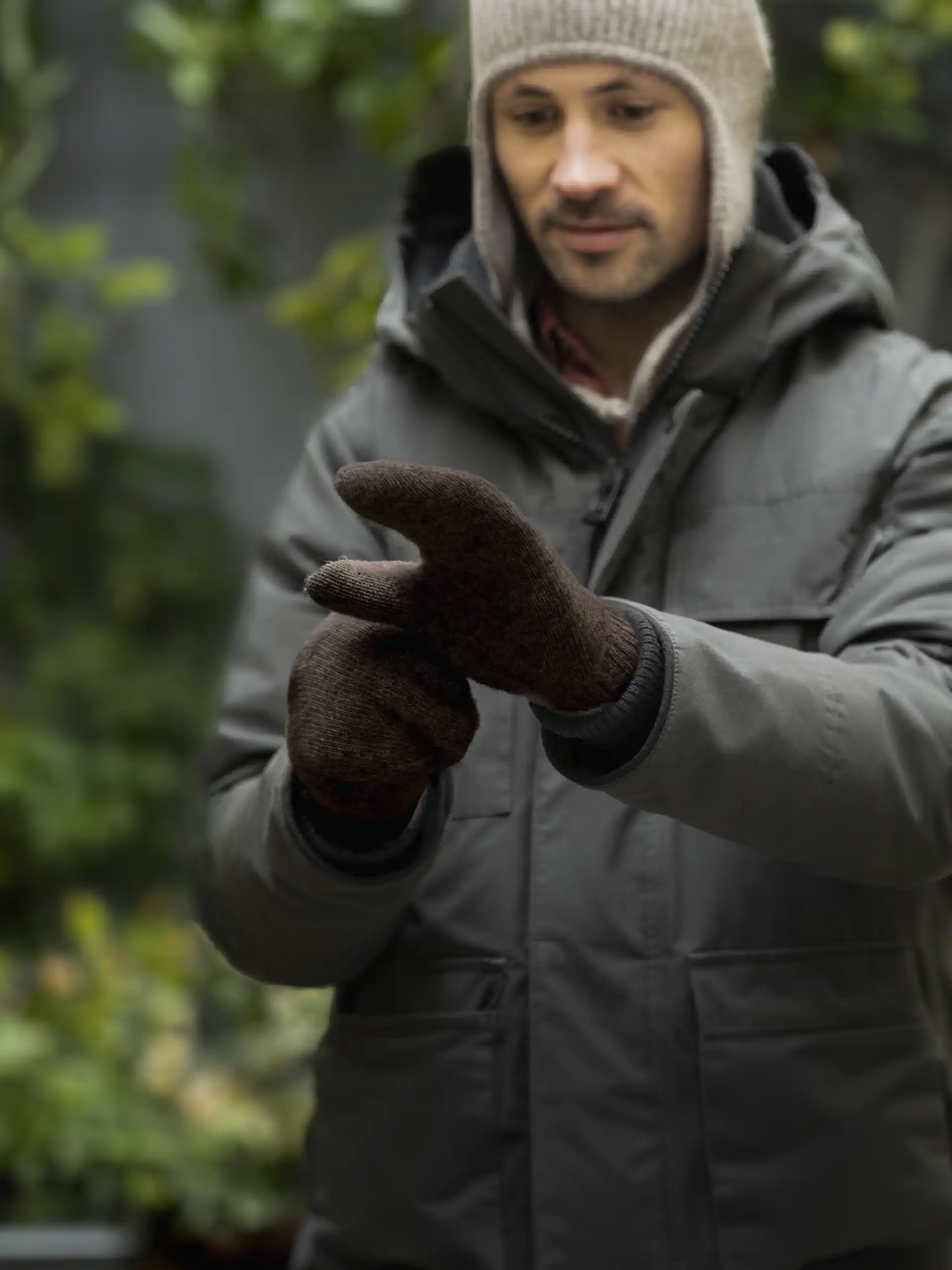 Homme habillé en manteau d'hiver avec des moufles en yack marron foncé.