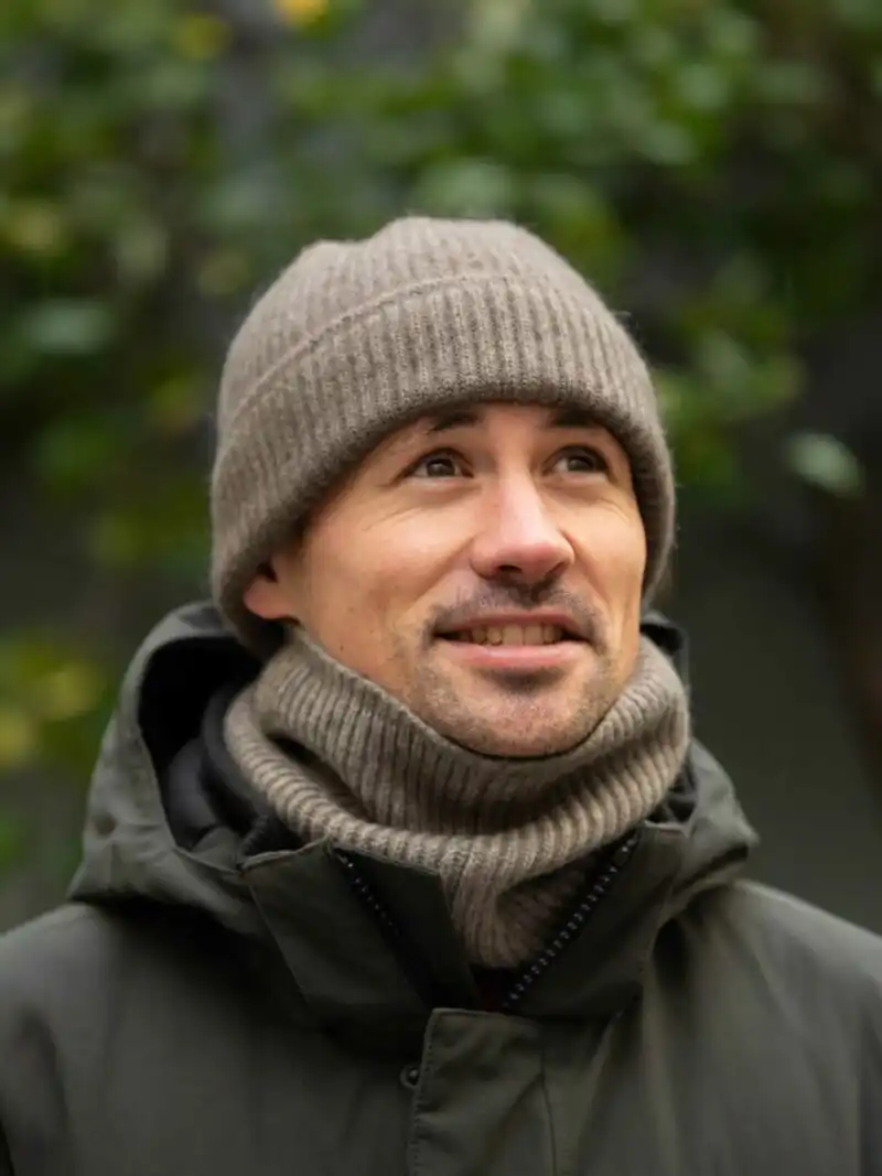 Homme souriant portant un BONNET YACK Gris cendré et une écharpe assortie en extérieur