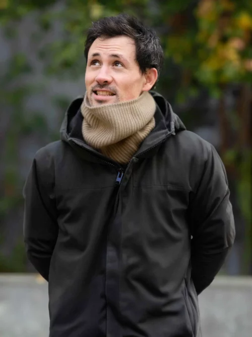 Homme portant un tour de cou chameau, en tricot, devant une porte. Ce chauffe-cou élégant et chaleureux est idéal pour l'hiver, fabriqué à partir de laine 100 % mongol.