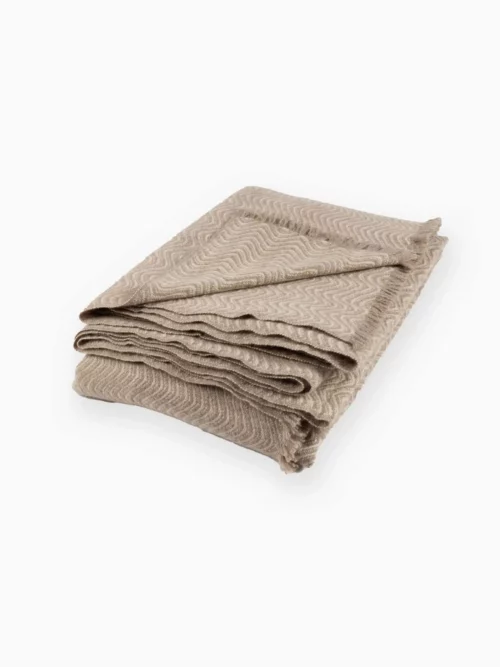 Plaid cachemire beige tricoté, soigneusement plié, prêt à être utilisé. Ce plaid en laine 100 % mongole, à la fois élégant et chaleureux, est parfait pour se chauffer pendant l'hiver. Produit de luxe disponible chez Mes Chaussettes Mongoles.