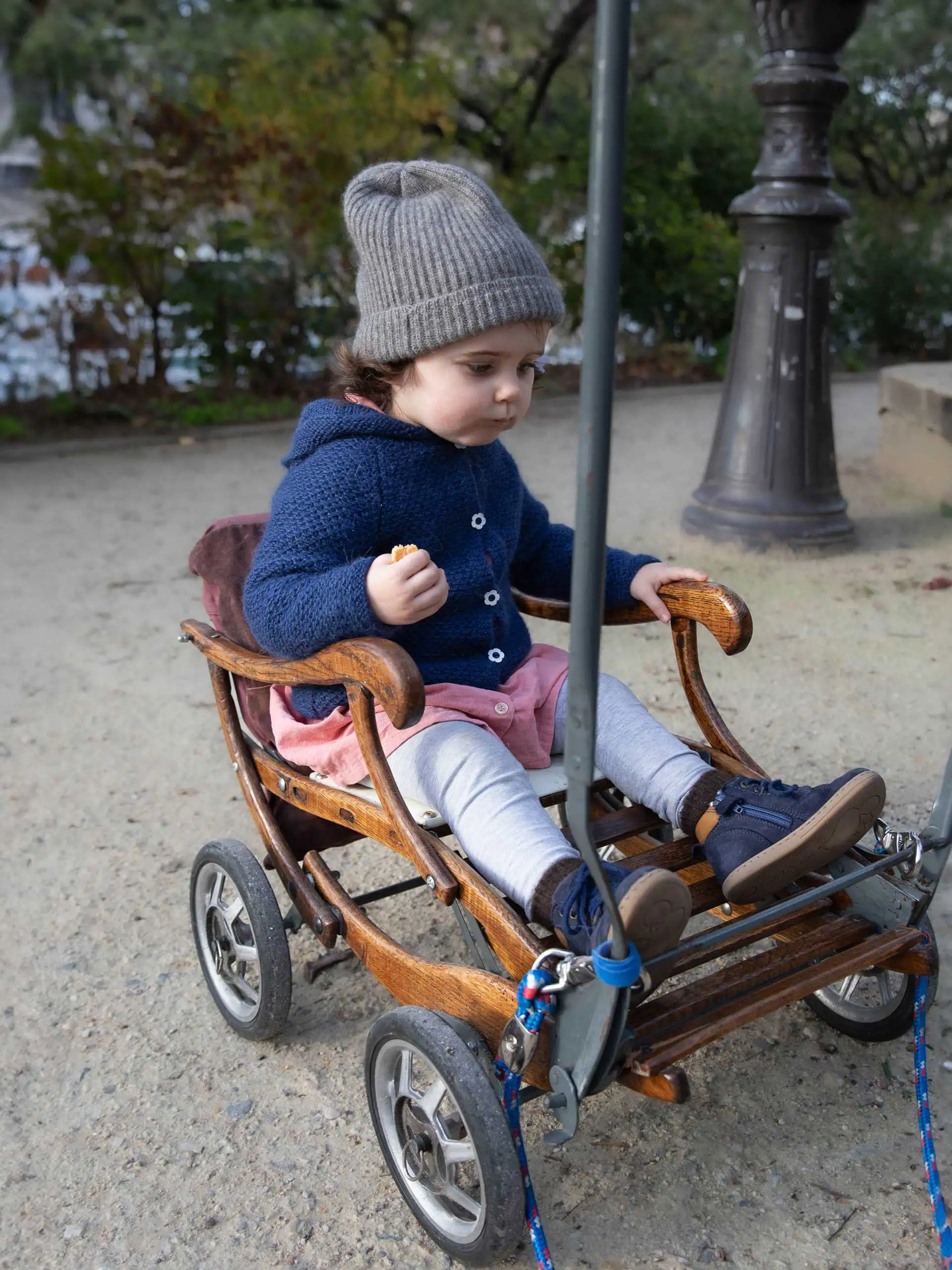 Enfant portant un bonnet enfant gris cendré en duvet yack de Mongolie, assis dans une poussette en bois.