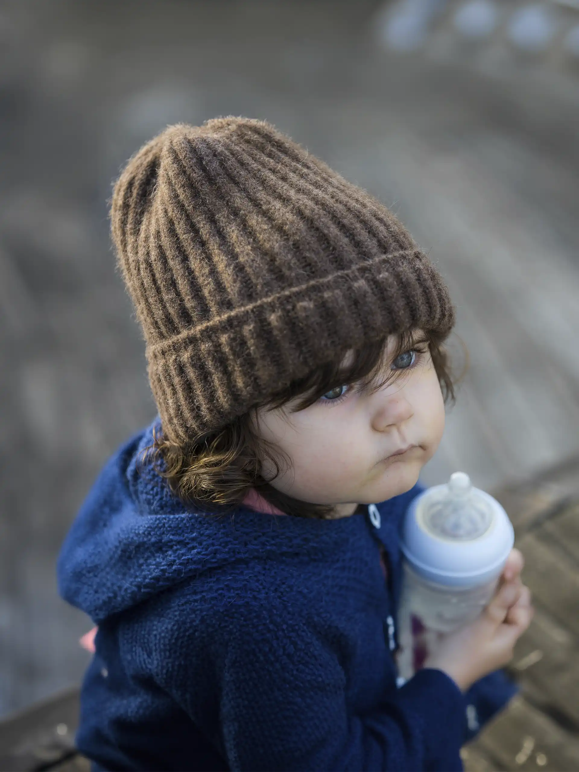 Enfant avec un bonnet en maille épaisse de duvet, idéal pour les saisons froides.