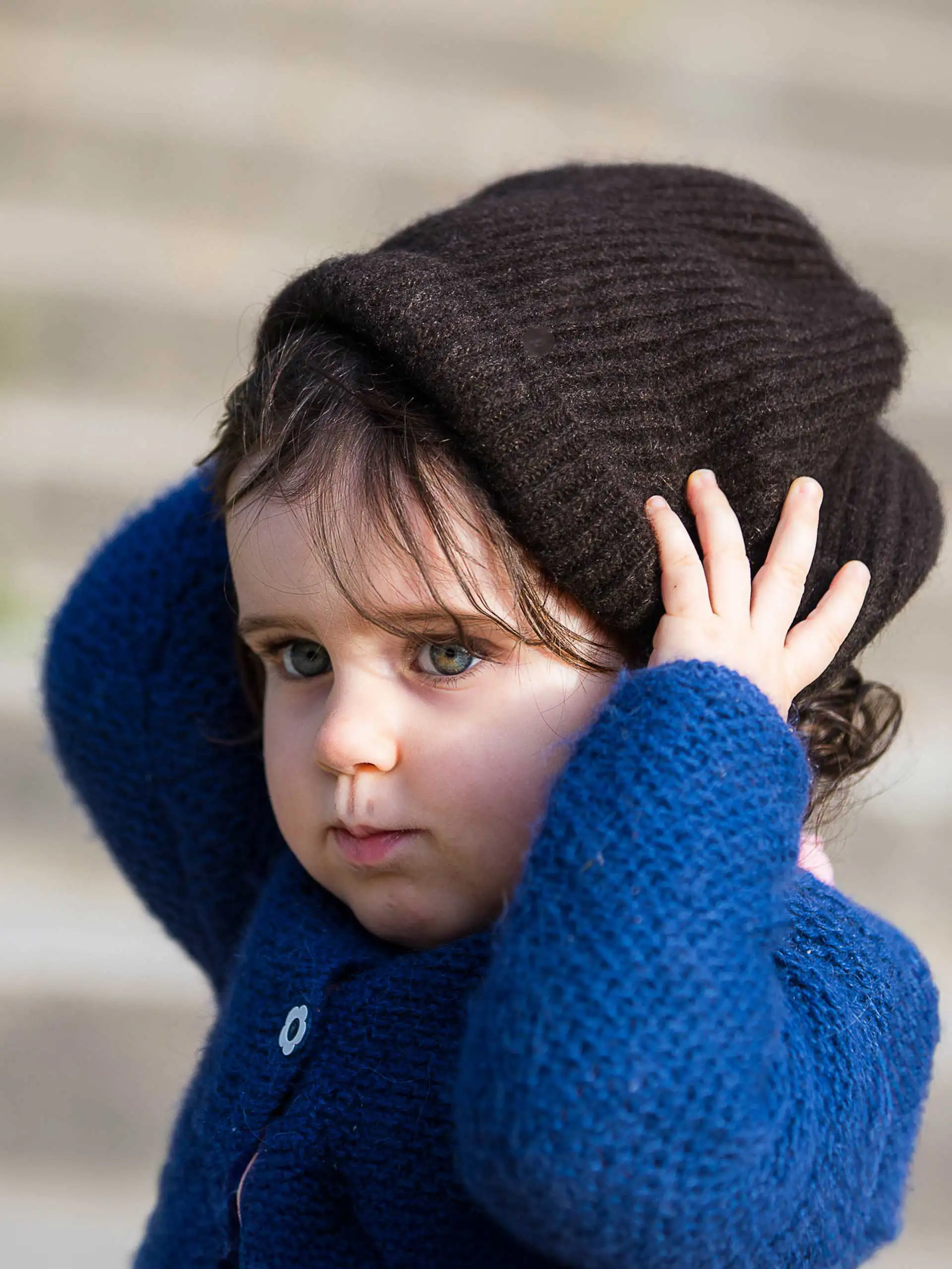Illustration d'un enfant ajustant son bonnet yack maille fine en duvet de Mongolie"