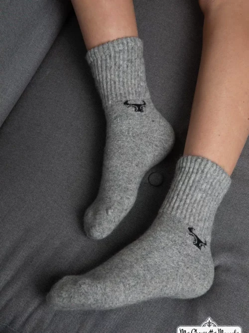 Chaussettes grises motif yack portées sur un canapé