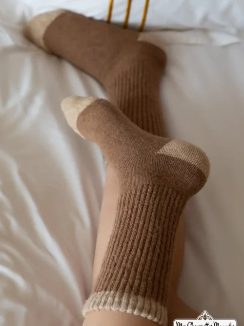 Personne allongée sur un lit portant des chaussettes hautes marron clair