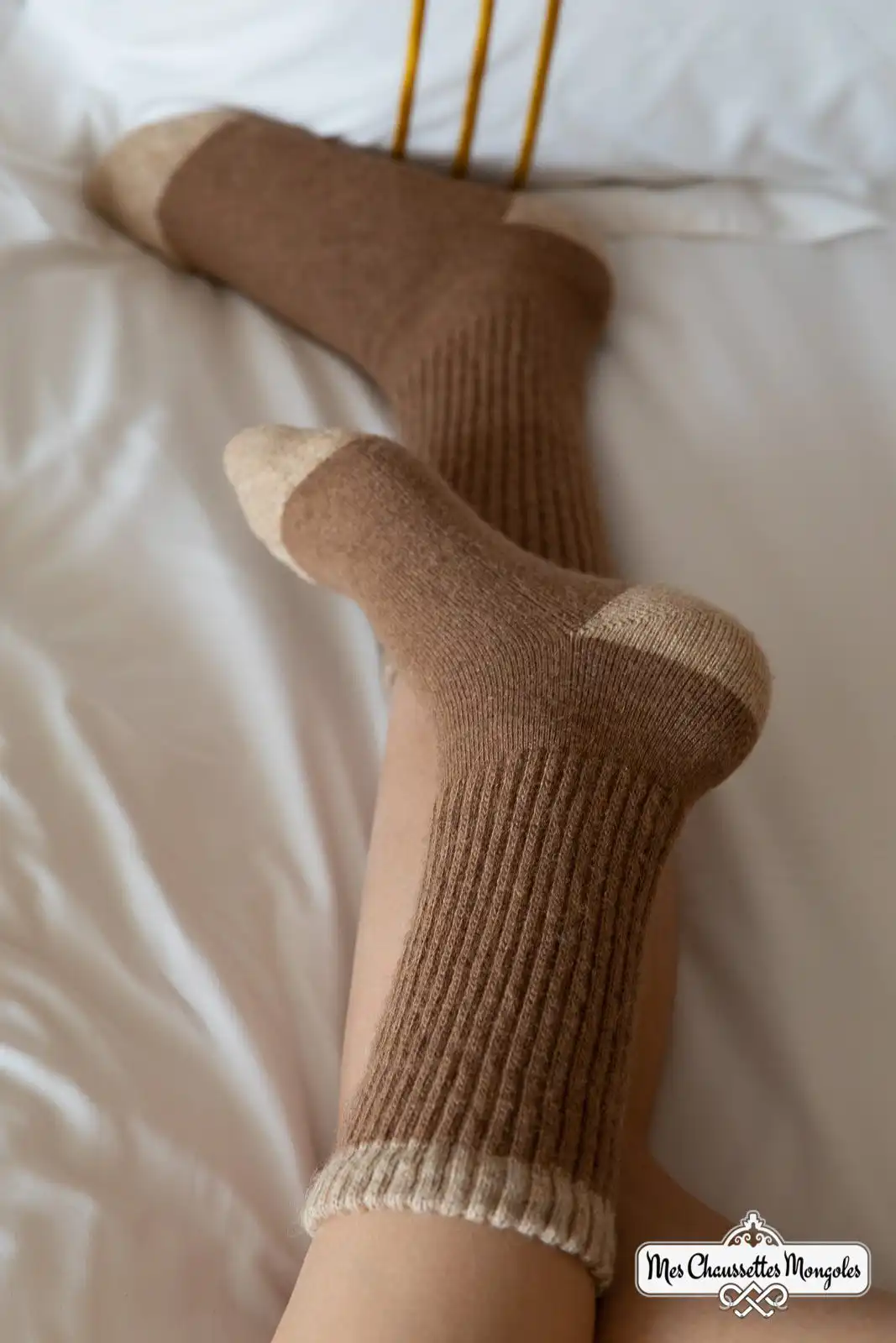 Personne allongée sur un lit portant des chaussettes hautes marron clair