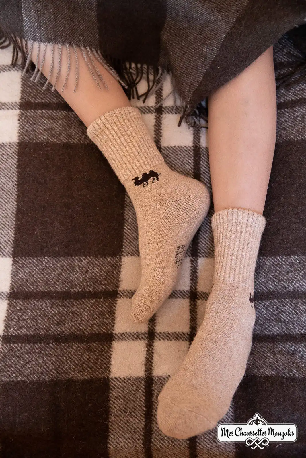 Femme allongée sur un lit avec des chaussettes motif chameau
