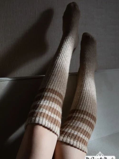Jambes de femme portant des chaussettes mouton longue crème allongée sur un canapé