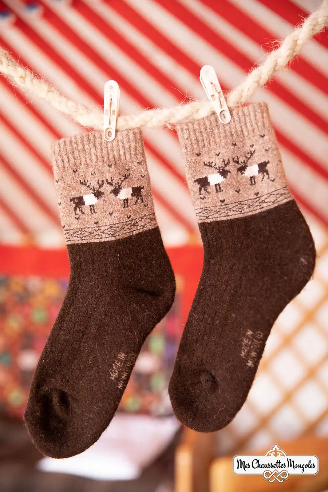 Une paire de chaussettes rennes marron foncé suspendues avec des pinces à linge.