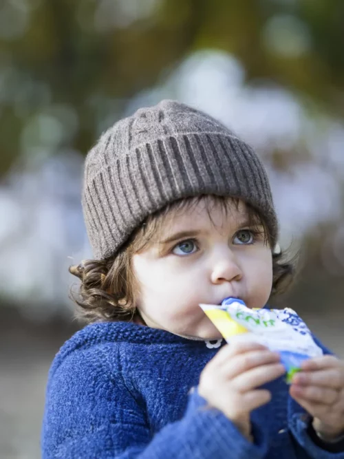 Enfant dégustant une collation en portant un bonnet yack enfant gris en duvet tricoté