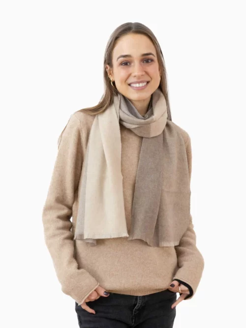 Femme souriante portant une écharpe cachemire beige tissée, idéale pour l'hiver