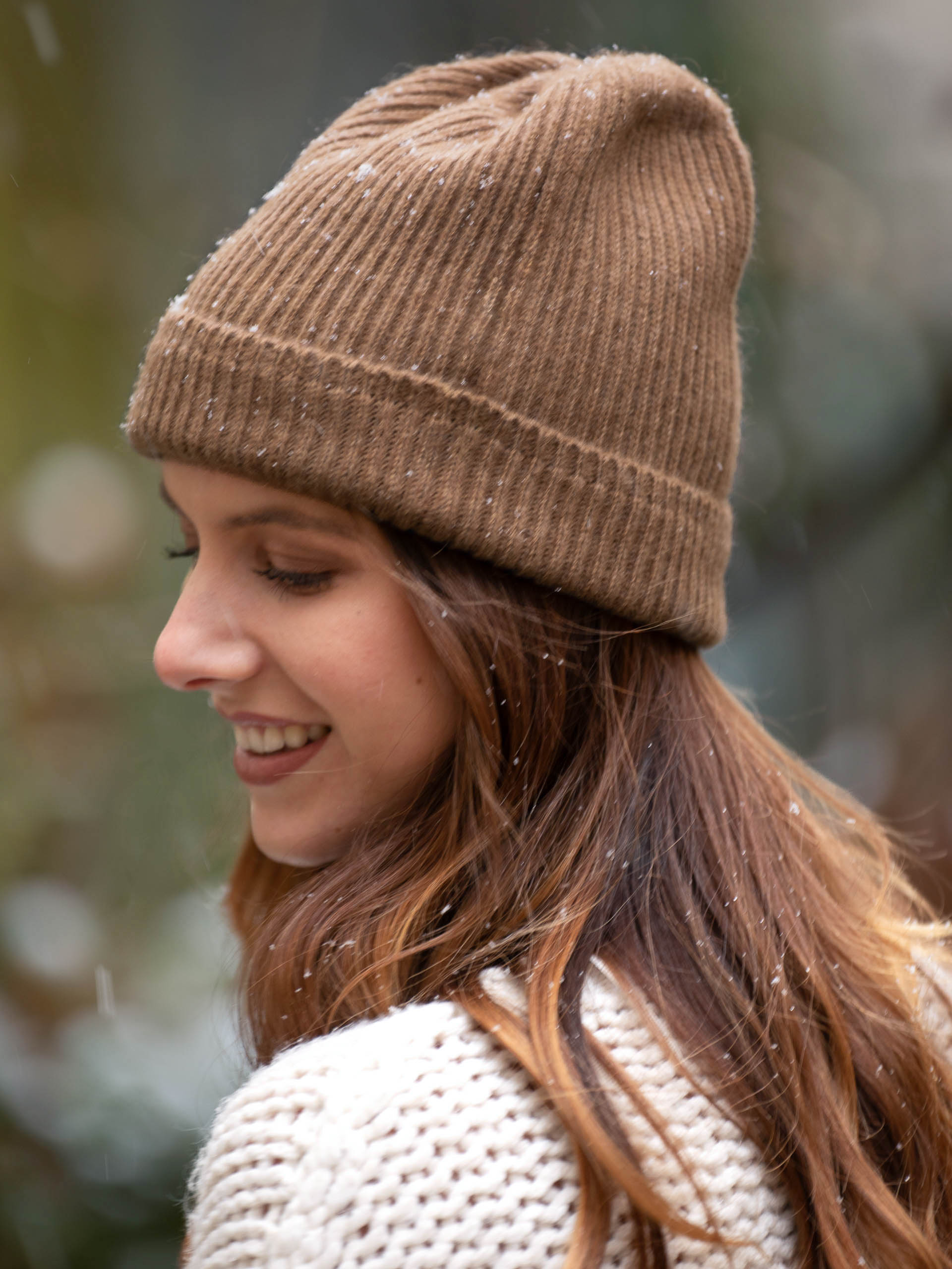 Femme souriante portant un bonnet camel sous la neige